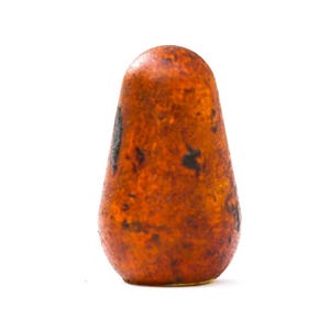 May include: A teardrop-shaped, orange-brown object with dark brown spots. The object has a smooth, rounded top and a slightly wider base. The surface appears to have a textured, aged appearance, suggesting it may be made of wood or a similar material.