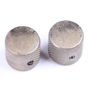 以下が含まれることがあります： 銀色のテクスチャ加工が施された、溝のあるエッジのノブが2つ。ノブは円形の上面と側面に小さな穴があります。これらのノブは、おそらく楽器または電子機器用です。