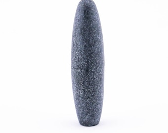 Puede incluir: Una piedra lisa de color gris oscuro, de forma ovalada, con una superficie ligeramente texturizada.