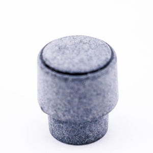 May include: A grey ceramic bottle stopper with a textured surface.