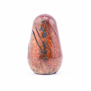 May include: A small, brown, ceramic, teardrop-shaped object with a textured surface.
