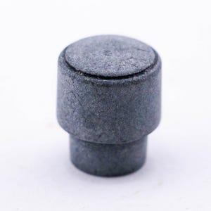 May include: A gray, round, ceramic knob with a textured surface.
