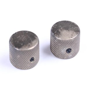 May include: Two silver-colored, cylindrical knobs with a textured, diamond-patterned surface. Each knob has a small, dark hole on its side. The knobs are likely for a musical instrument or electronic device.