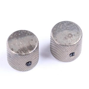 May include: Two silver-colored, cylindrical knobs with a textured, ridged surface. Each knob has a small, dark-colored indicator. The knobs are likely for a musical instrument or electronic device.