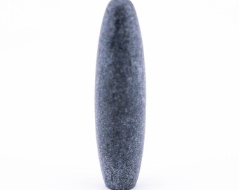 以下が含まれることがあります： 丸みを帯びた上部とわずかにテクスチャ加工された表面を持つ、灰色の細長い石の乳棒。乳棒は無地の濃い灰色で、白い背景に配置されています。このキッチンツールは、材料を粉砕するために使用されます。