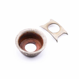 May include: A silver metal washer with a slightly rusted interior and a separate silver metal washer with a rounded shape.