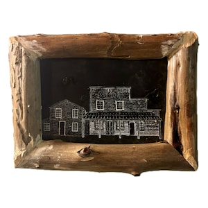 May include: A framed black and white drawing of two buildings with white trim. The frame is made of natural wood with a rough texture.