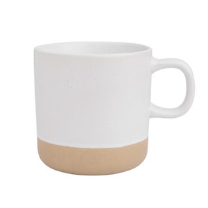 May include: A white ceramic mug with a speckled glaze and a beige band around the bottom.