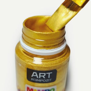 a close up of a jar of gold paint with a brush in it