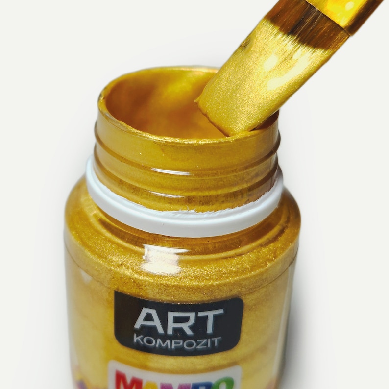 a close up of a jar of gold paint with a brush in it