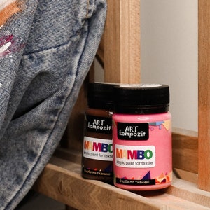 May include: Two bottles of acrylic paint for textile, labelled "MAMBO" in a colourful font. The bottles are brown and pink and have black lids. The text on the labels reads "ART kompozit" and "acrylic paint for textile" in Russian.