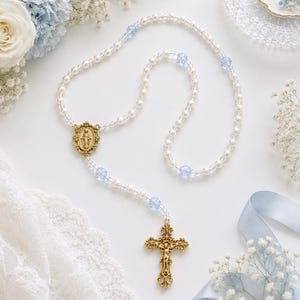 Crèmekleurige Swarovski-parelrozenkrans, gouden fleur-de-lis-kruisbeeld, blauwe kristallen accenten, bruids- of dooprozenkrans