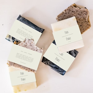 May include: Four bars of handmade soap with labels that say "Paris, France" and "Rose | Smoke | Cypress". The soap is a mix of white and black with a speckled appearance.
