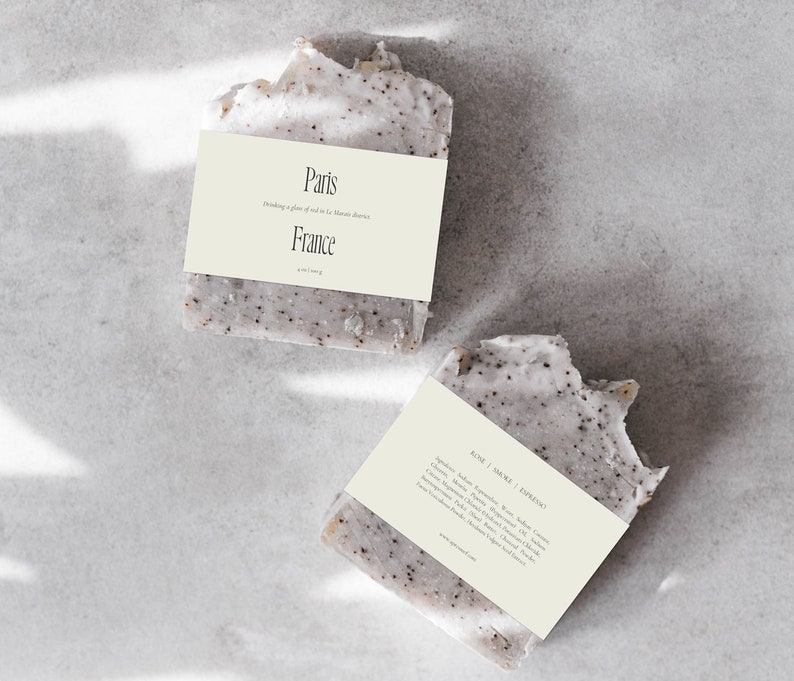 May include: Two bars of handmade soap with a light brown label. The top label reads "Paris" and "Dreaming of a place of old in the Marais district" and "France". The bottom label reads "Rose | Ambre | Figuier" and lists ingredients including shea butter, coconut oil, and olive oil.