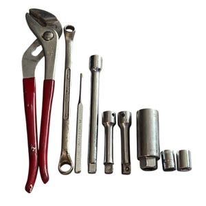 Puede incluir: Un conjunto de herramientas manuales, que incluye alicates con mangos rojos, llaves y vasos. Las herramientas son de metal y están dispuestas sobre un fondo blanco. Los alicates miden unos 25 cm de largo.