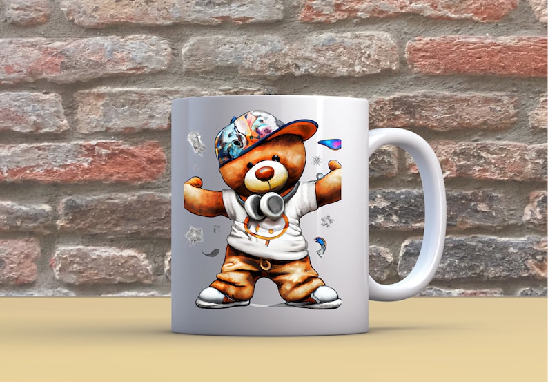 Pu&ograve; includere: Tazza in ceramica bianca con un'illustrazione colorata di un orso che indossa un cappello e delle cuffie. L'orso &egrave; in piedi con le braccia distese e indossa una camicia bianca con un cerchio nero. La tazza ha un manico bianco.