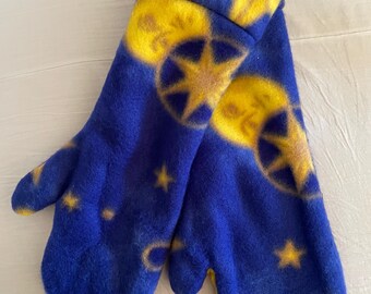 Può includere: Un paio di guanti in pile blu con un design celeste. I guanti presentano un motivo di lune, stelle e cerchi gialli. I polsini sono ripiegati e l'interno è giallo.