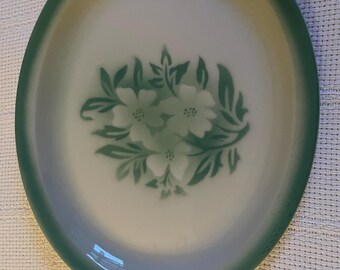 Può includere: Piatto ovale da portata con centro bianco e bordo verde. Il centro presenta un motivo floreale nelle tonalità del verde. Il piatto è probabilmente realizzato in ceramica o porcellana ed è adatto per servire cibo.