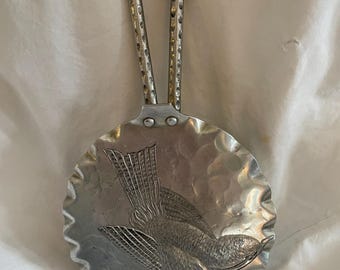 Può includere: Un cucchiaio da portata in argento con finitura martellata e un design a forma di uccello. Il cucchiaio ha un manico ad anello con una superficie testurizzata.