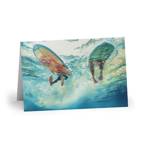 May include: Greeting card featuring an underwater view of two surfers with their surfboards. The image shows the surfers' legs and the bottom of their surfboards in the water. The water is a mix of blues and greens.