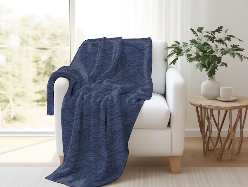 May include: A blue throw blanket with a wavy pattern, draped over a white armchair in a living room setting.
