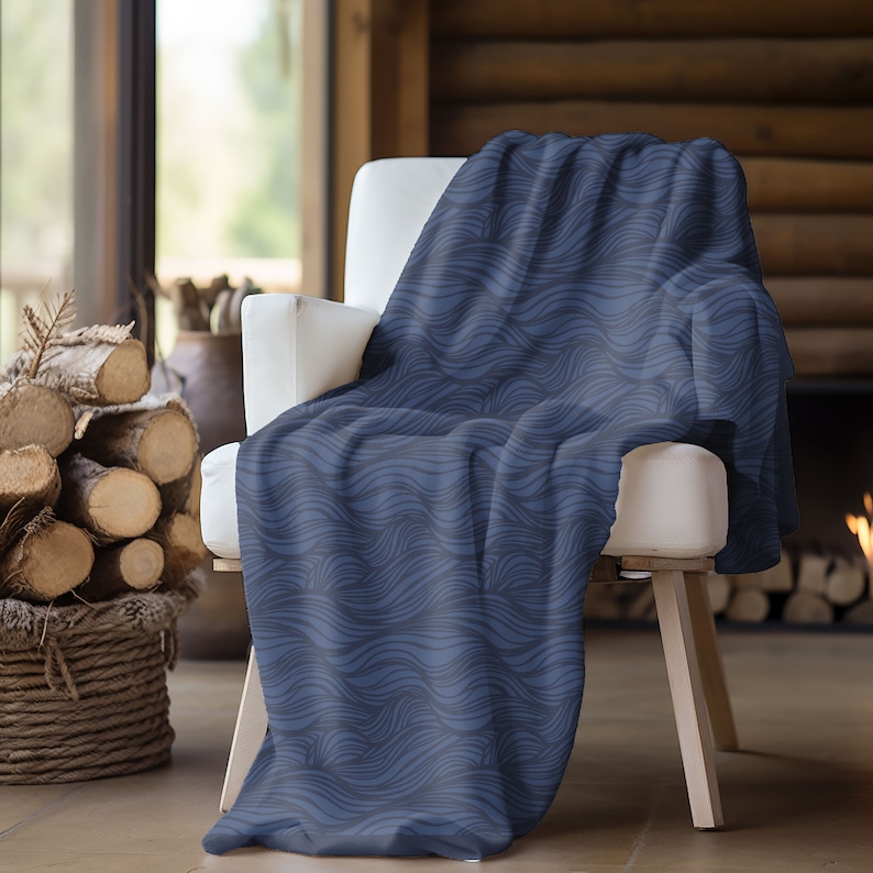 May include: A blue throw blanket with a wavy pattern, draped over a white armchair. The blanket is made of soft, plush fabric and is perfect for adding a touch of warmth and style to any room.
