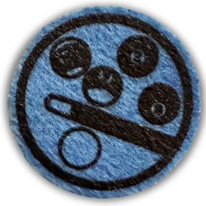 May include: A blue fabric circle with a black design of a circle with four smaller circles inside. The smaller circles have a black and white design.