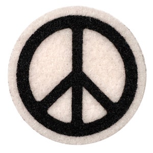 May include: A white peace sign with a black outline. The peace sign is made of a soft, fuzzy material.
