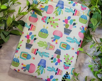 May include: A white fabric pouch with a colorful cactus print. The pouch features a variety of cacti in different colors and styles, including pink, blue, green, and yellow. The pouch is perfect for storing small items like jewelry, makeup, or electronics.
