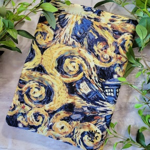 May include: A blue and yellow fabric book cover with a swirling pattern reminiscent of Vincent van Gogh's Starry Night.