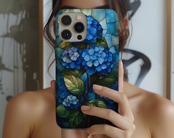 May include: A smartphone case featuring a stained-glass design of blue hydrangea flowers with green leaves. The case has a dark blue background with a mosaic pattern. The phone case has a camera bump with three lenses.
