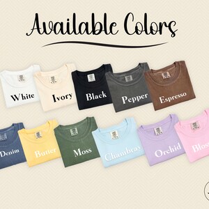 May include: A selection of t-shirts in various colours, including white, ivory, black, pepper, espresso, denim, butter, moss, Chambray, orchid, and blossom. The shirts are folded and arranged in a row, with the colour names printed below each shirt.
