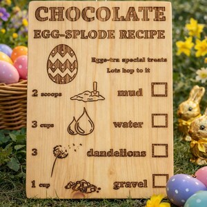 Pu&ograve; includere: Tavola di legno con incisa la scritta "CHOCOLATE EGG-SPLODE RECIPE". La ricetta include ingredienti come fango, acqua, denti di leone e ghiaia. Un oggetto decorativo a tema pasquale.