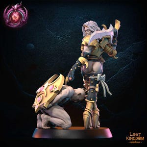 May include: A detailed miniature figurine of a warrior in gold and black armor, holding a sword. A kneeling figure holds a shield with pink accents. The figurine is on a black base. The Lost Kingdom miniatures logo is visible.