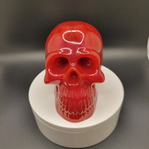 May include: A red glitter skull figurine. The skull is made of resin and has a glossy finish.