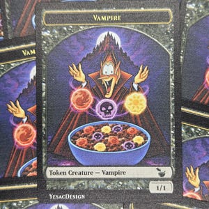 May include: A rectangular trading card titled Vampire featuring a cartoon vampire character with hands raised above a blue bowl of cereal. The card displays three glowing orbs, text reading Token Creature - Vampire, 1/1, and YesacDesign.