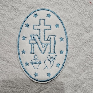 Könnte beinhalten: Ein gestickter Aufnäher mit blauem und weißem Design. Das zentrale Bild ist eine ovale Form mit blauem Rand. Im Inneren befindet sich ein Kreuz über dem Buchstaben "M", mit Sternen, einem Herzen und einem Schwert. Der Aufnäher befindet sich auf weißem Stoff.