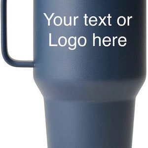 Puede incluir: Un vaso Yeti azul con asa y tapa de acero inoxidable. El vaso tiene el texto "Your text or Logo here" impreso en el lateral.