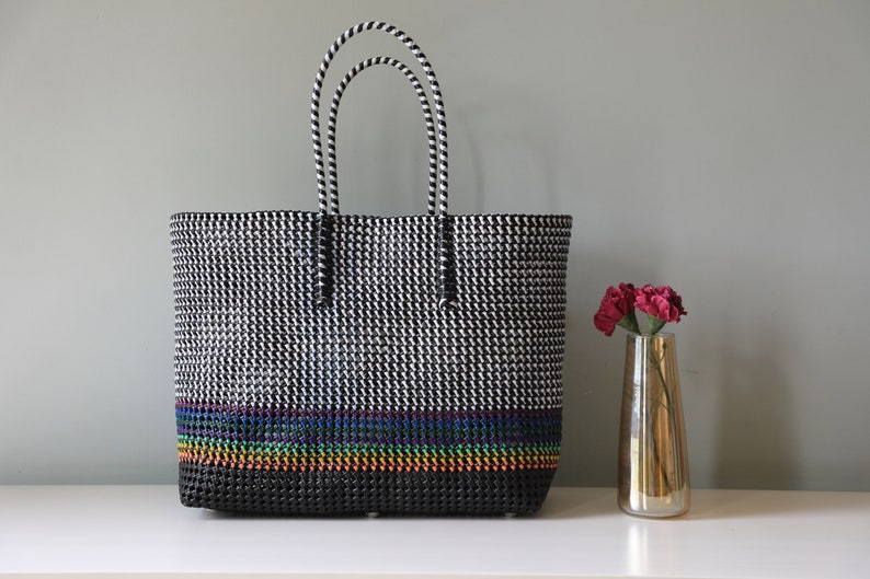 May include: Black and white tote bag with a rainbow stripe design. The bag has two black and white striped handles.
