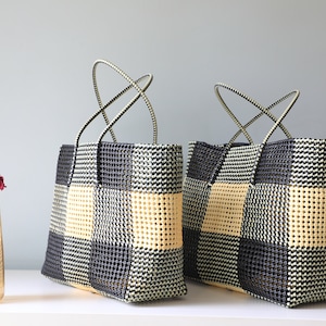 May include: Two black and cream checkered tote bags with black handles. The bags are made of woven plastic and have a square shape.