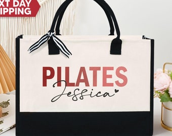 May include: A white canvas tote bag with black trim and handles. The bag has the text "PILATES Jessica" printed on the front in red and black.