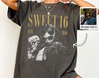May include: A charcoal gray short-sleeve t-shirt featuring a custom graphic print. The design includes the text SWEET 16 EST. 2010 in gold lettering above a black and white photograph of a person wearing sunglasses and a jacket.