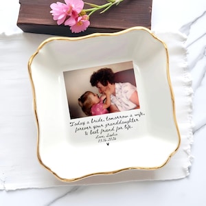 May include: A white ceramic square dish with a gold rim, featuring a photo of a woman and child. The dish has a scalloped edge and text that reads "Today a bride, tomorrow a wife, forever your granddaughter & best friend for life."