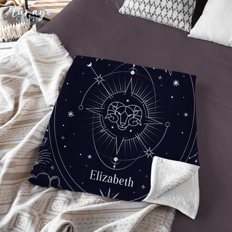 May include: A navy blue fleece blanket with a white design of a ram's head inside a circle with stars and the name "Elizabeth" printed below.