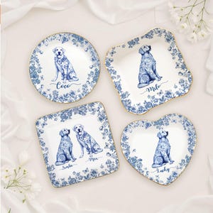 May include: Set of four decorative plates with blue and white floral patterns and gold rims. Each plate features a watercolor illustration of a dog and a name: Coco, Milo, Simba, Max, and Lucky. The plates are in various shapes.