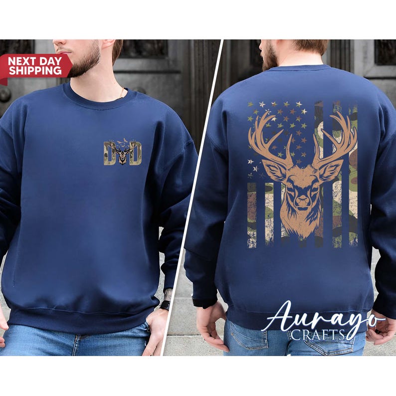 May include: Navy blue sweatshirt with a deer graphic on the back, featuring a camouflage and American flag design. The front has a small gold emblem with the letters "DD". The text "NEXT DAY SHIPPING" is visible.