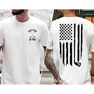 Peut inclure: T-shirt blanc avec un motif noir de clubs de golf crois&eacute;s et le texte "Best Dad By Par". Le dos du t-shirt pr&eacute;sente un motif de drapeau am&eacute;ricain d&eacute;labr&eacute; avec un club de golf.