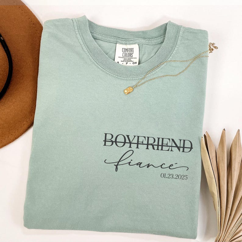 May include: A light green t-shirt with the text "Boyfriend fiance" and the date "01.23.2025" printed on it.