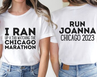 May include: Two white t-shirts with black text. The front shirt says "I ran up a tab watching the Chicago Marathon". The back shirt says "Run Joanna Chicago 2023".