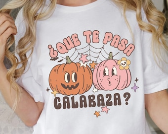 Puede incluir: Camiseta blanca con un gráfico de dos calabazas de dibujos animados y el texto "¿Que te pasa calabaza?" en español.